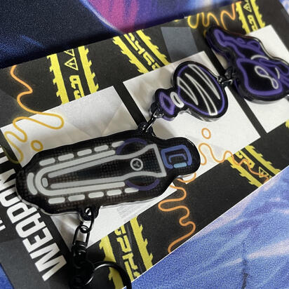 One of the neon Splatoon weapons ticker designs turned into a linked keychain on top of its decorative packaging